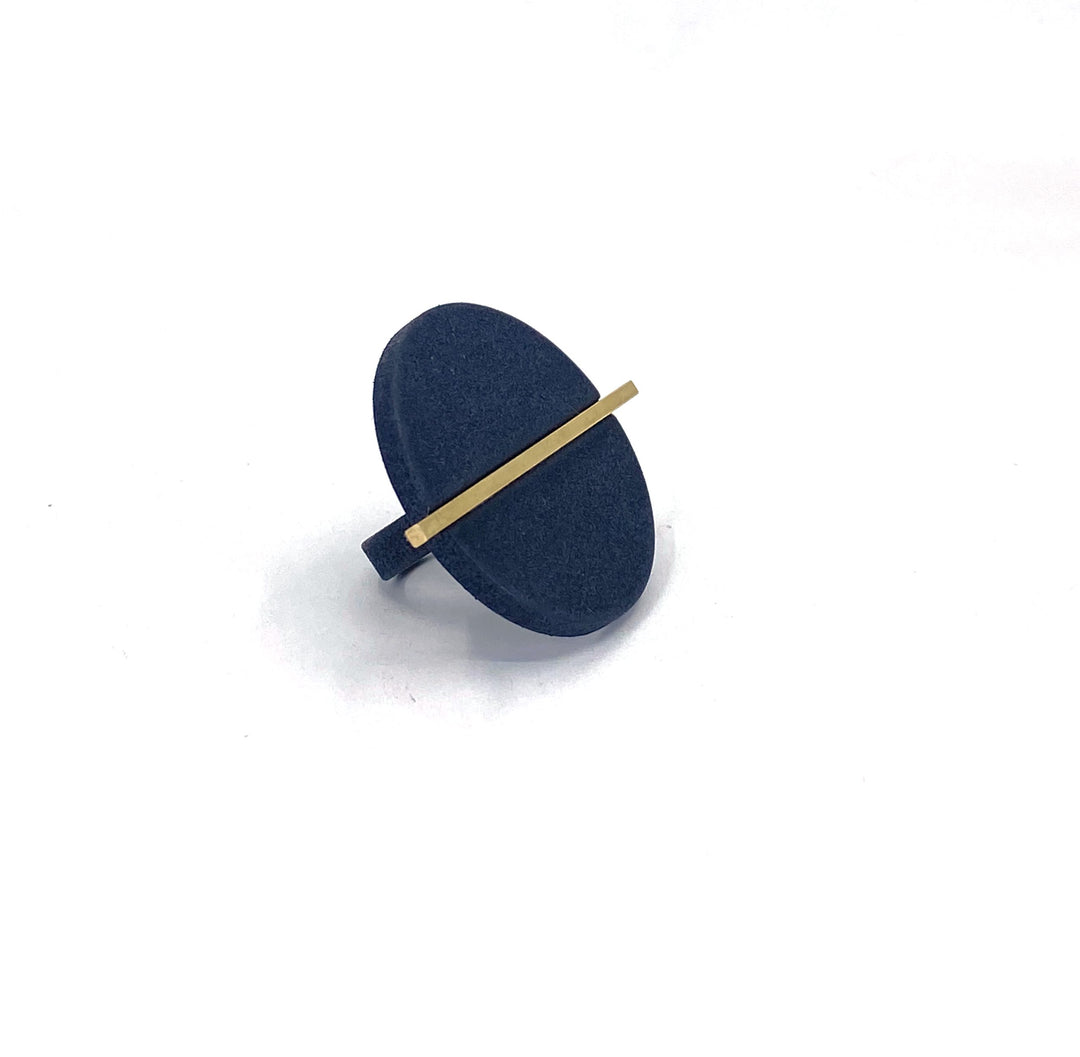 The Elsiem Vibe Disc & Bar Ring is a modern statement piece featuring a large oval matte dark blue face with a thin gold bar across its diameter, shown on a plain white background.