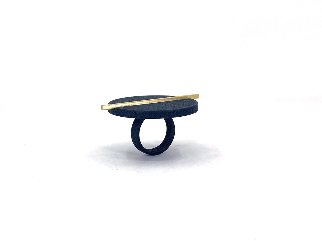 The Elsiem Vibe Disc & Bar Ring features a wide, flat, dark circular top with a slim diagonal gold bar, crafted from SLS Nylon and shown against a plain white background.