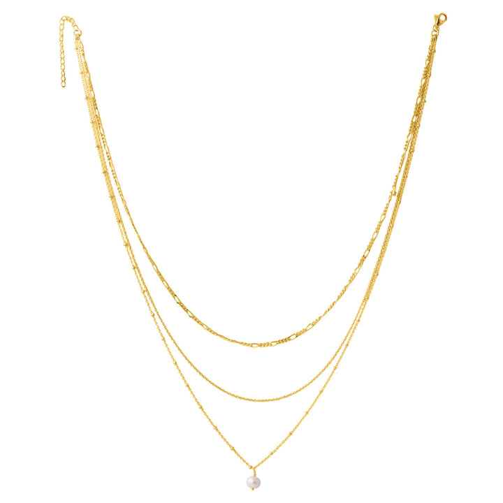 The Carmen necklace by Watermelon Tropical features an elegant triple-chain design, artfully incorporating layers of varying lengths. The shortest chain showcases a delicate white pearl pendant, while the other two chains are composed of refined gold links. This versatile layered gold vermeil necklace exudes sophistication and style.
