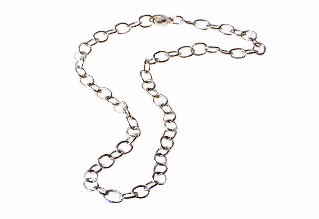 A Detlef Menard Wide Anchor Chain with large, rounded links crafted from recycled sterling silver is arranged in an asymmetrical, slightly curved fashion against a white background. The uniformly spaced and interconnected links give the handcrafted chain a simple yet elegant appearance.