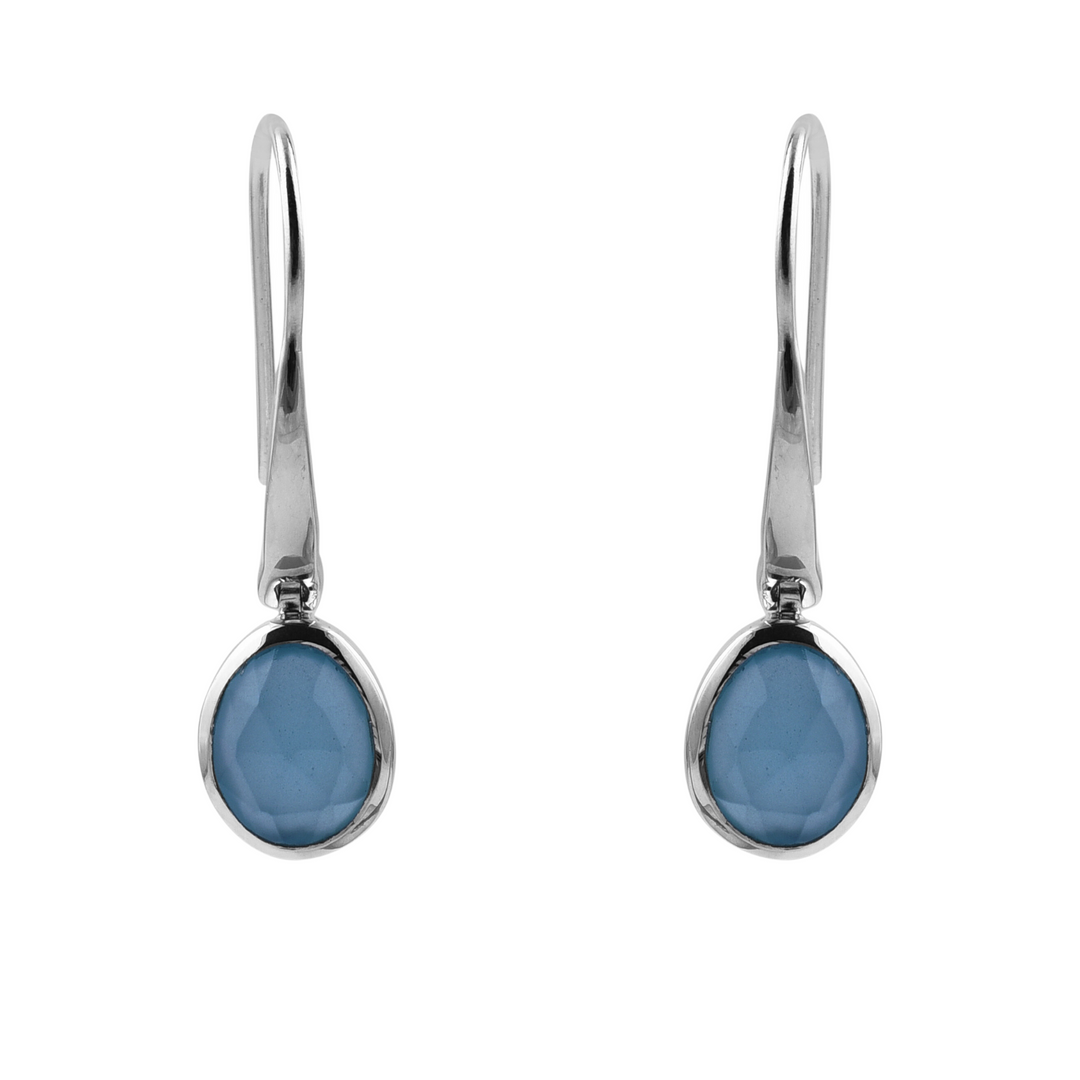 The Aqua Chalcedony Earrings by Watermelon Tropical feature oval-shaped aqua chalcedony gemstones encased in sleek sterling silver bezels. Emphasizing a modern design with a hook-style fastening, these earrings stand out elegantly against a plain white backdrop.