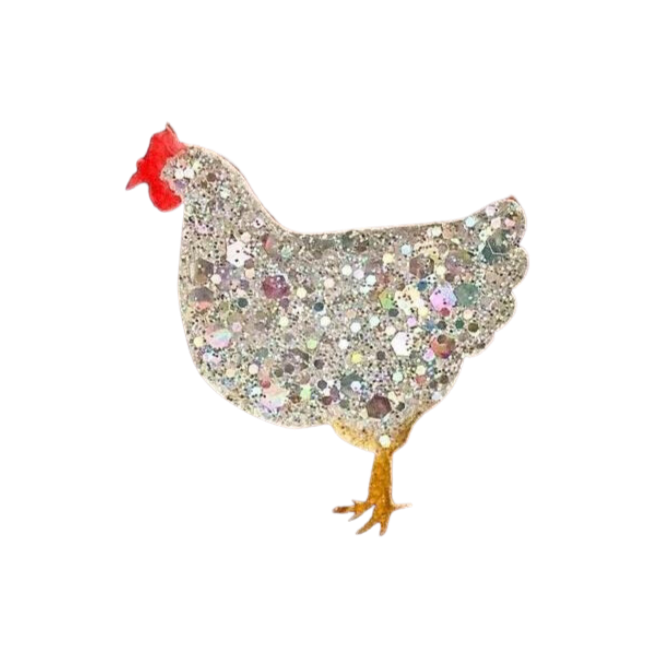 A Naoi Chicken Pin Brooch Silver Medium adorned with multicolored glitter and sequins. The chicken, reminiscent of handpainted wooden chickens, has a red comb, yellow beak, and yellow legs in a simplistic design. The brooch sparkles with various shades of glitter, giving it a festive appearance.