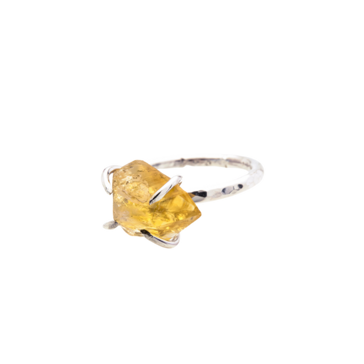 The Caroline Stokesberry-lee Citrine Rock Ring features a raw Citrine gemstone set in an irregular, natural shape. The gemstone is held in place by delicate prongs, showcasing its natural facets. The ring band is slim and polished, highlighting the bright, raw beauty of the stone.