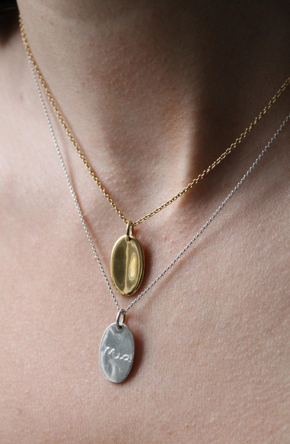 A necklace with an organic oval shaped pendant with a small indent on the front.