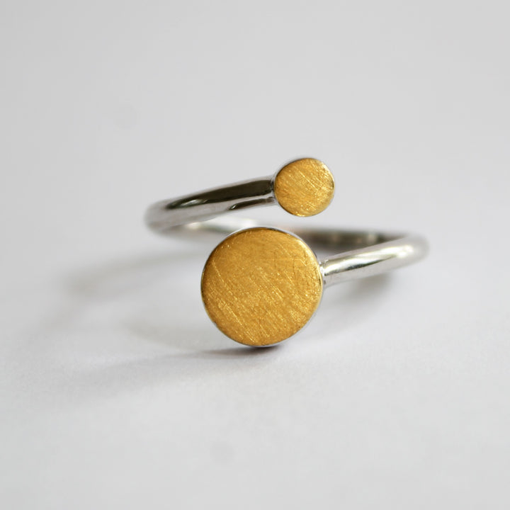 The Archeol Ring by Gallardo & Blaine Designs features two flat, round gold vermeil discs of different sizes on each end of an open band made from sterling silver, shown against a plain white background.