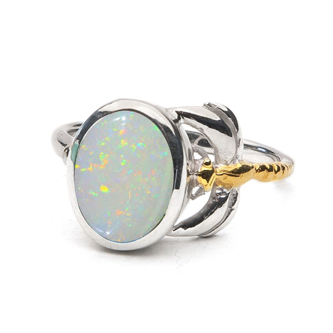 The Daydream Ring in various gemstones by Gallardo & Blaine Designs is an adjustable gold-plated sterling silver ring, featuring an oval opal with iridescent colors and a bold gold anchor accent on the band.