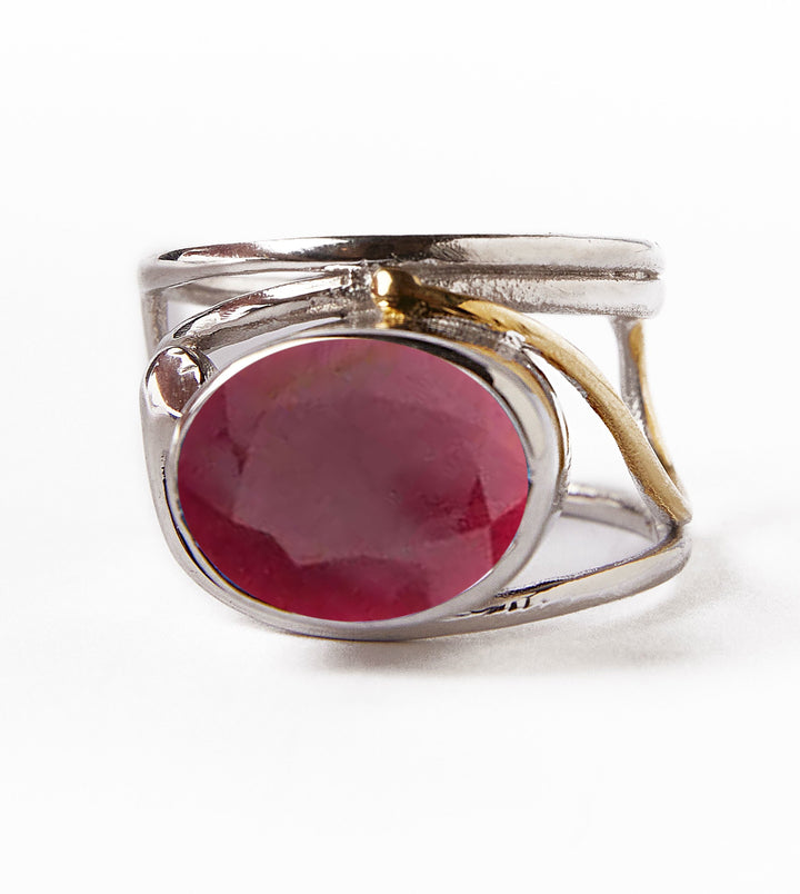 The Horizontal Ring by Gallardo & Blaine Designs features a large, round red gemstone centerpiece on a silver and gold-plated band with an open, textured modern design, combining elegance with contemporary style.