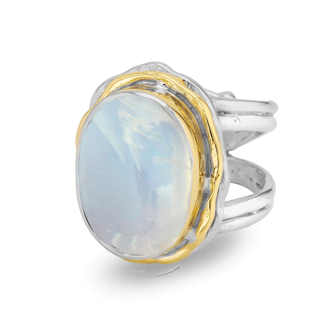 The Magnolia Ring in silver gold & various gemstones by Gallardo & Blaine Designs features a sterling silver band with a unique, intertwined design. At its center, a large, oval-shaped moonstone is set in a gold bezel, creating a stunning statement ring that exudes elegance and charm.