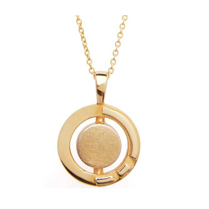 The Urú Large Pendant & Chain by Gallardo & Blaine Designs is a delicate gold pendant necklace featuring a circular design. The pendant has a smooth, round center encircled by a donut-shaped gold border with cut-out sections and three small, rectangular accents near the bottom. Inspired by Irish heritage jewelry, the chain is made of small interlinked loops.