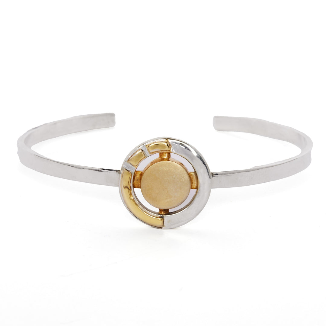The Urú Cuff Silver & Gold by Gallardo & Blaine Designs is a sterling silver open Celtic cuff with a gold and silver geometric centerpiece and raised gold disc, inspired by Irish heritage jewelry traditions.