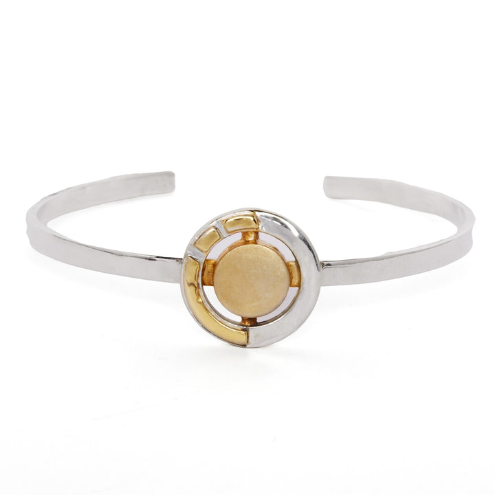 The Urú Cuff Silver & Gold by Gallardo & Blaine Designs is a sterling silver open Celtic cuff with a gold and silver geometric centerpiece and raised gold disc, inspired by Irish heritage jewelry traditions.