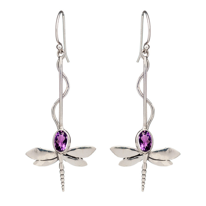 A pair of Willow Earrings in Various Gemstones by Gallardo & Blaine Designs with elongated hooks. The dragonflies boast detailed wings and bodies, featuring oval-shaped purple gemstones set in their centers. The twisted pattern of the hooks elegantly leads to the shimmering dragonfly design.