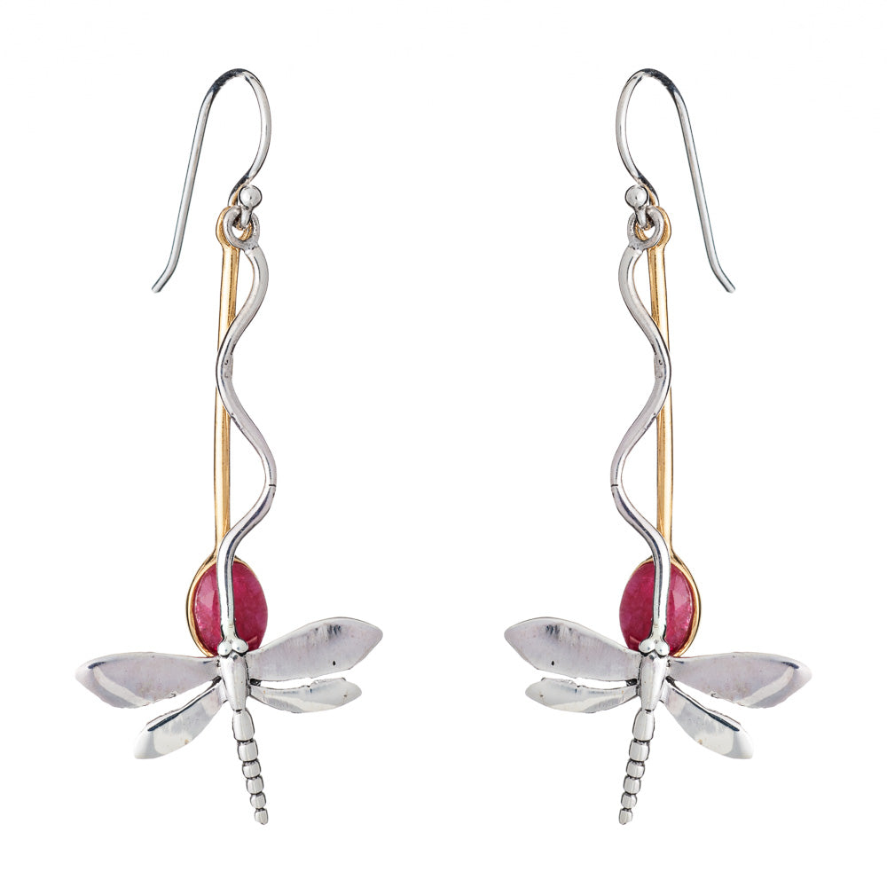 The Willow Earrings in Various Gemstones by Gallardo & Blaine Designs are a pair of dangle earrings designed to resemble silver dragonflies, featuring silver-toned bodies with gold-toned accents and red oval-shaped gemstones as the rear part of the bodies. The earrings have hook attachments for wearing.