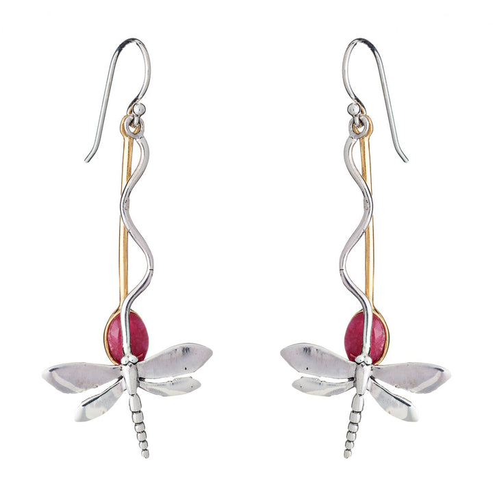 The Willow Earrings in Various Gemstones by Gallardo & Blaine Designs are a pair of dangle earrings designed to resemble silver dragonflies, featuring silver-toned bodies with gold-toned accents and red oval-shaped gemstones as the rear part of the bodies. The earrings have hook attachments for wearing.