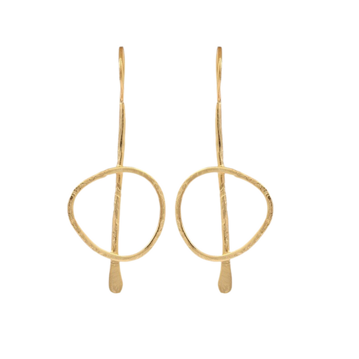 Gold plated, statement, drop earrings. The earring starts with a thin, slightly curved hook that loops through the earlobe. A slender vertical metal bar extends downward from the hook, with a slightly uneven, hand-forged texture. Attached to the vertical bar is a loosely shaped, slightly irregular circle. This frame has a hammered texture.