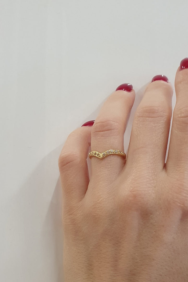 A hand with red-painted nails wears the Georgia Charal Imagination Wishbone Ring, crafted in sterling silver with colorful zircons, shown against a plain white background.
