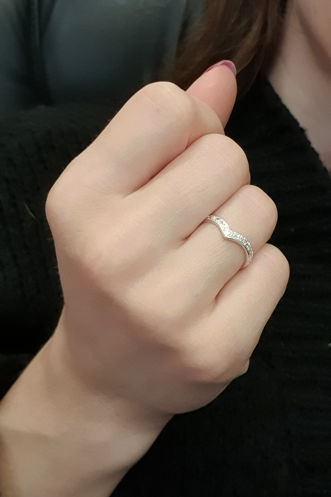 A hand with light skin wears the Georgia Charal Imagination Wishbone Ring with colorful zircon on the ring finger, paired with a black textured fabric.