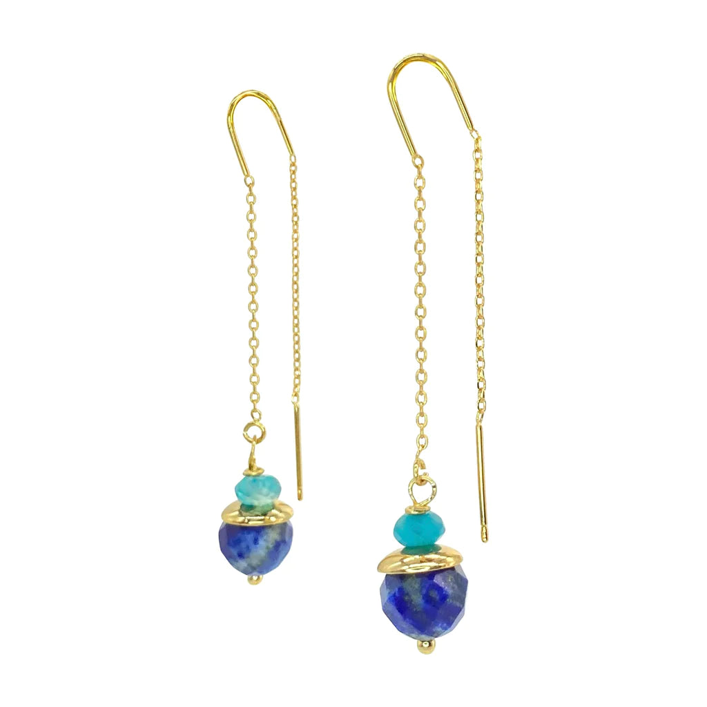 The Aria V Kiki Earrings boast 16k gold plated threader chains adorned with faceted natural lapis lazuli stones and turquoise gemstones. Each earring features a captivating blue lapis lazuli bead at the bottom, topped by a smaller turquoise bead and gold accents, creating an elegant dangling effect.
