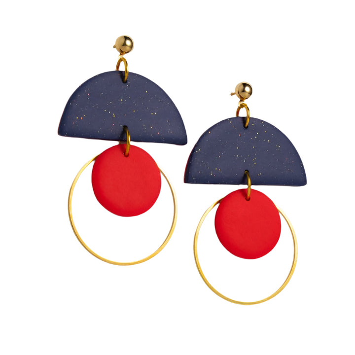 The Olivia Midnight Earrings by Culu Design are handmade polymer clay earrings featuring gold studs, dark blue semicircles with gold speckles, large gold hoops, and bright red accents, inspired by Wicklow jewelry.