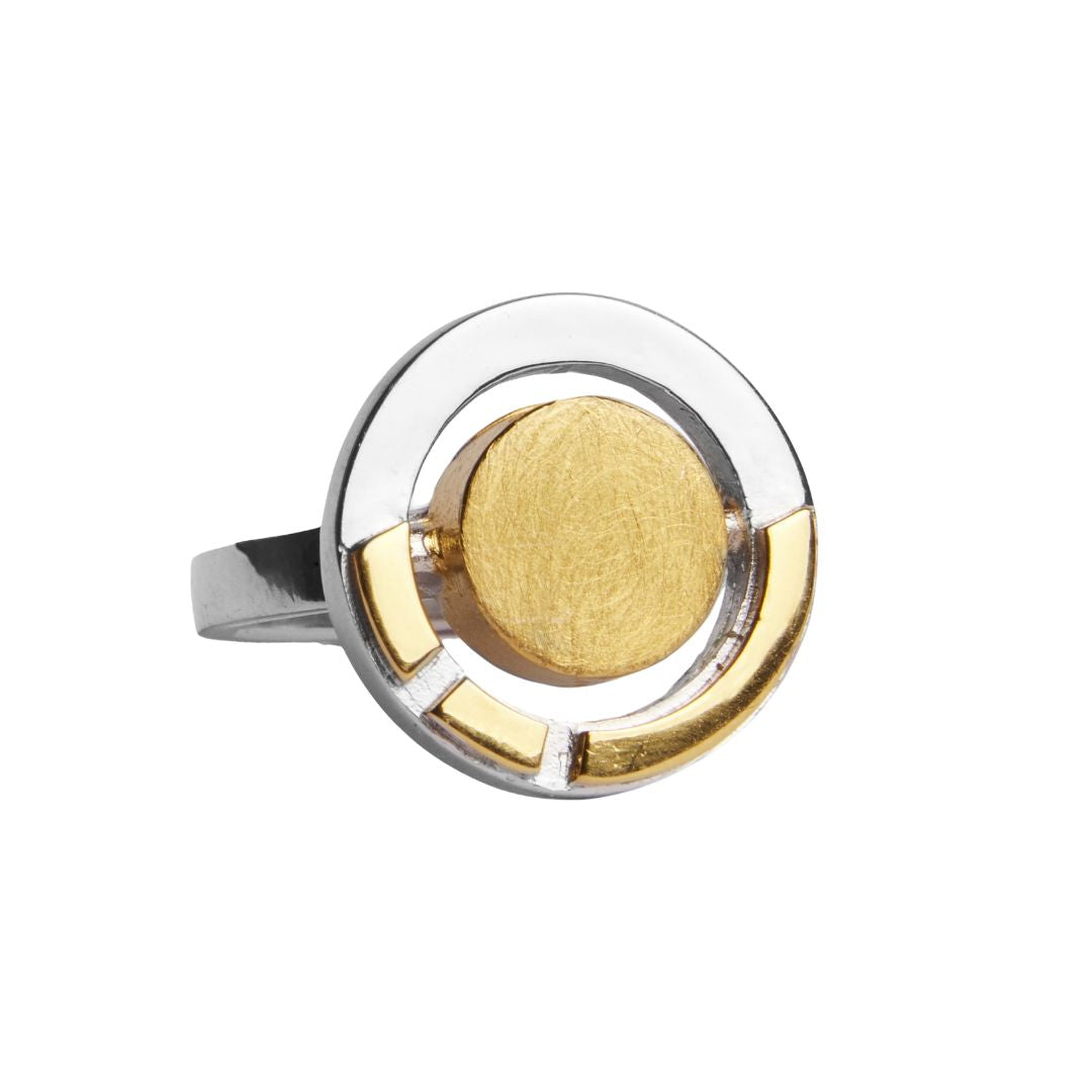 The Urú Ring by Gallardo & Blaine Designs is a silver statement ring with a modern circular design, featuring a large central gold disc and gold accents—an eye-catching piece inspired by Irish heritage jewelry.