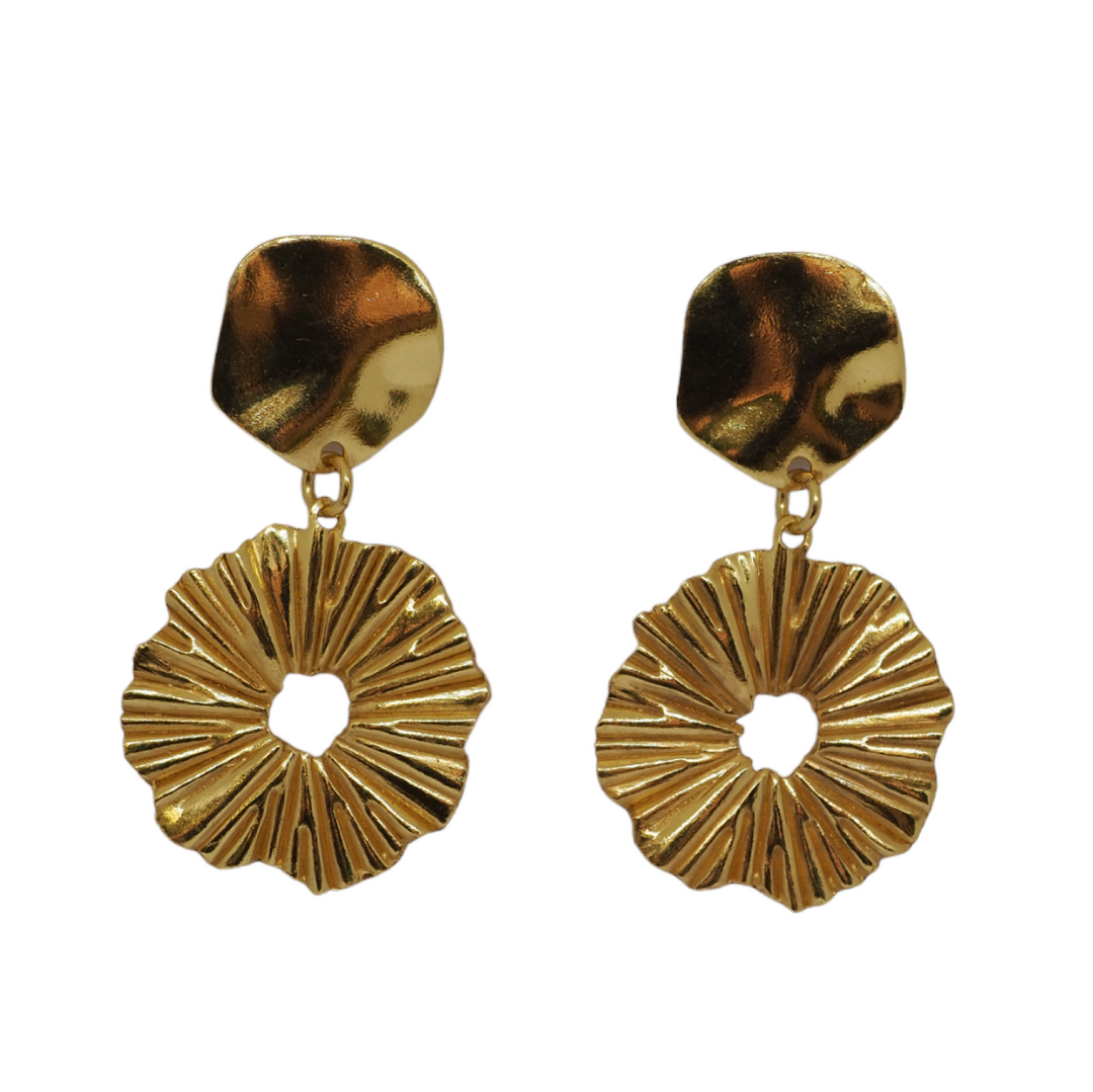 Gold drop, statement earrings. The top of the earring  is a small, irregularly shaped metallic piece that attaches to the earlobe. It has a slightly curved surface with a subtle, organic texture, resembling a petal.   Hanging from the top piece is a circular pendant with a hole in the centre, giving it a donut-like shape. The surface of this pendant features radiating ridges, resembling the folds of a flower or the texture of a sunburst. The ridges create depth and reflect light dynamically.