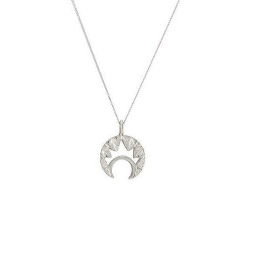 A Cosmic Boulevard Moon & Moon Silver Pendant with a thin chain features a moon pendant in the shape of a crescent, surrounded by a circle of pointed, geometric designs. The hand-engraved pendant hangs centrally from the chain.