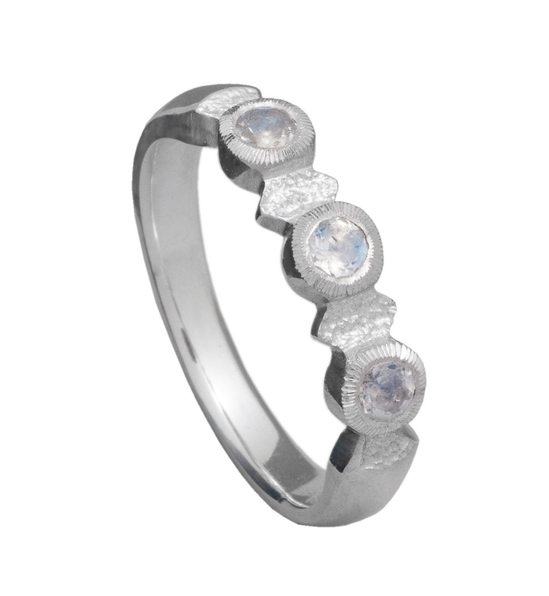 The Midnight Ring by Aud is a sterling silver ring with a matte finish, featuring three round, faceted moonstones set in a row along the band. The stones are evenly spaced and held in place by individual bezels, creating a simple, elegant design that evokes the tranquility of midnight.