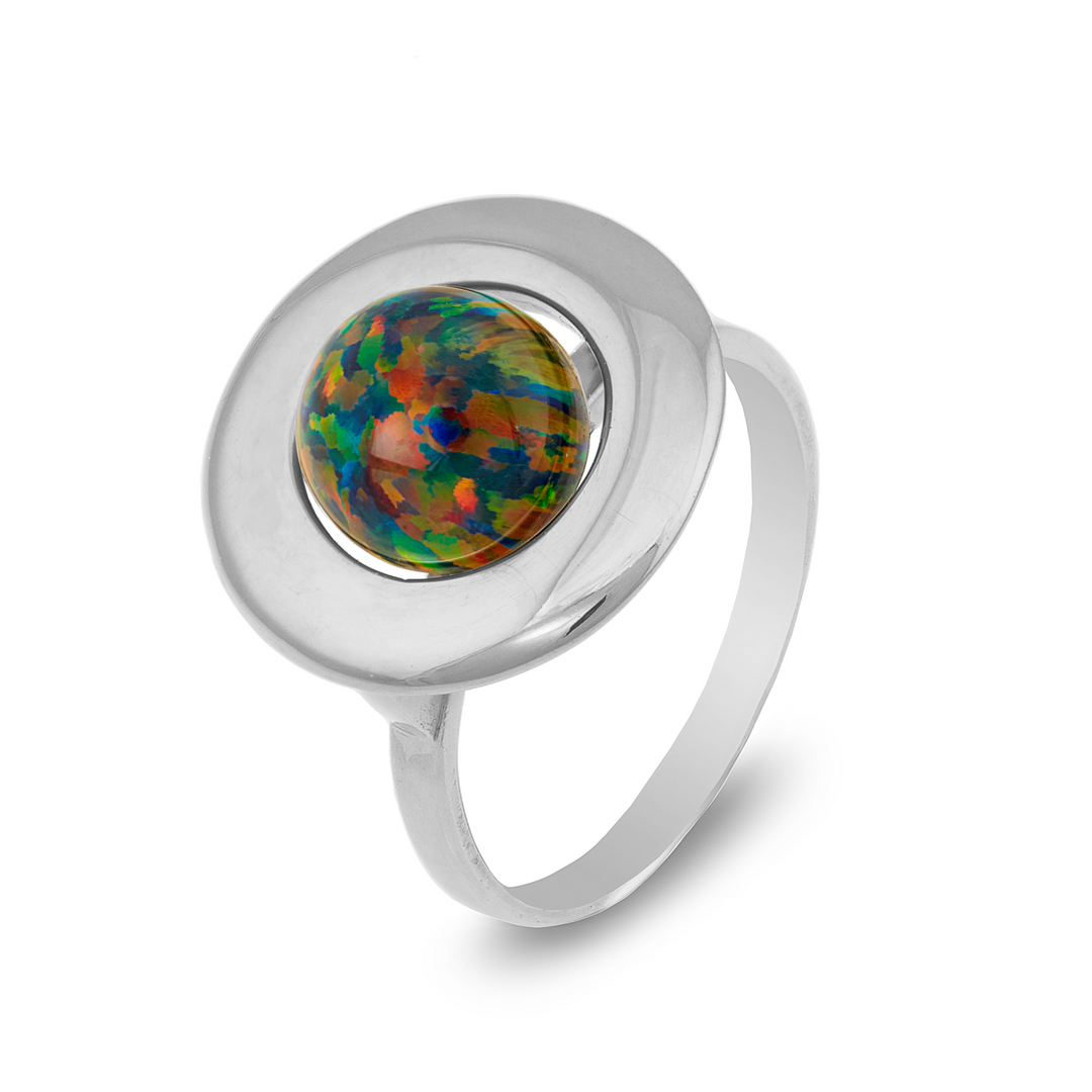 The Cosmic Boulevard Home Planet Black Opal Sterling Silver features a round, iridescent opal stone set in the center. The opal displays a vibrant mix of red, green, and blue hues and is mounted on a flat, circular silver base. The band is simple and sleek, complementing the intricate opal design perfectly.