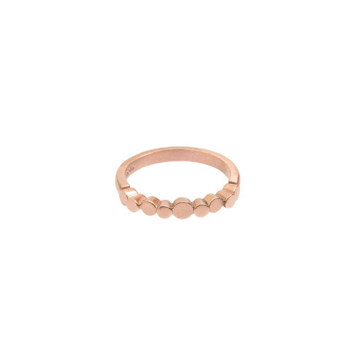 A delicate 9ct rose gold ring featuring a series of small, round discs evenly spaced along the top half of the band. This Irish hallmarked piece has a minimalist and modern design, with a smooth and polished finish. The background is plain white. The product is the Flow Pebble Ring 9ct Rose Gold by Miriam Wade.