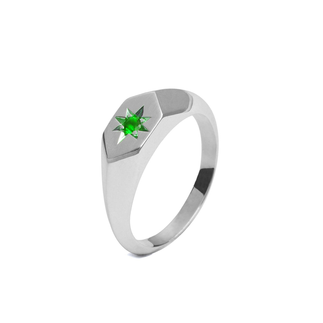 A sleek Silver Star ring featuring a vibrant green May birthstone set in a geometric star-shaped design. The band is smooth and polished, giving the Starlight Emerald Birthstone Signet Ring by Cosmic Boulevard a modern, minimalist look.