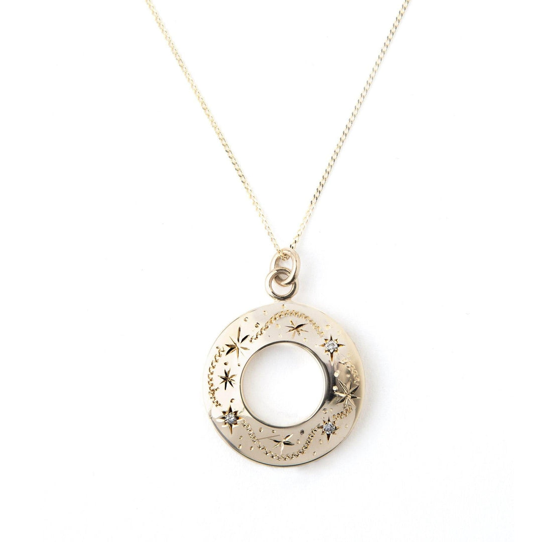 A delicate 9ct yellow gold necklace featuring a circular pendant with intricate star and moon engravings. The center of the pendant is hollow, adding an elegant touch to the design. The Diamond Shooting Star Pendant 9ct Yellow Gold by Cosmic Boulevard hangs from a fine gold chain, capturing the essence of a shooting star.