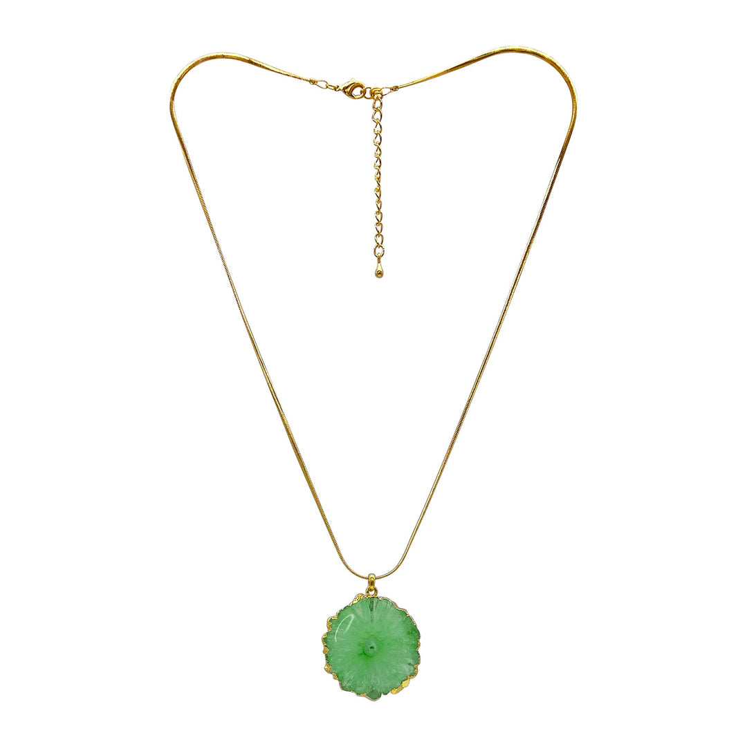 An Aria V Geya Necklace features a delicate gold plated snake chain with an adjustable clasp. It holds a green jade pendant shaped like a flower with intricate details, framed in a gold setting. The jade is smooth and polished, adding a touch of elegance to the piece.