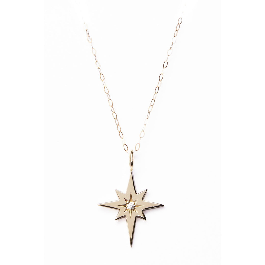 The Diamond Polaris Pendant by Cosmic Boulevard is a minimalist necklace featuring a delicate chain and a pendant shaped like a compass star with a small diamond in the center. The gold-toned or sterling silver chain has evenly spaced links, adding to the elegance of this handmade jewellery piece.