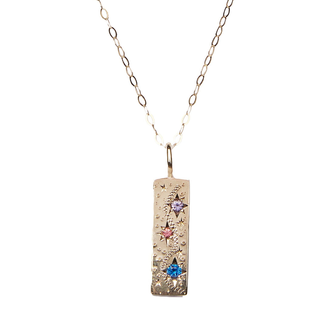 A gold rectangular pendant necklace with small textured dots and three star-shaped gemstones in blue, pink, and purple. This Oh my Sapphire Stars 9ct Yellow Gold Necklace by Cosmic Boulevard features a pendant that hangs from a delicate chain with small, interlocking oval links. A beautiful piece of handmade jewellery to cherish.