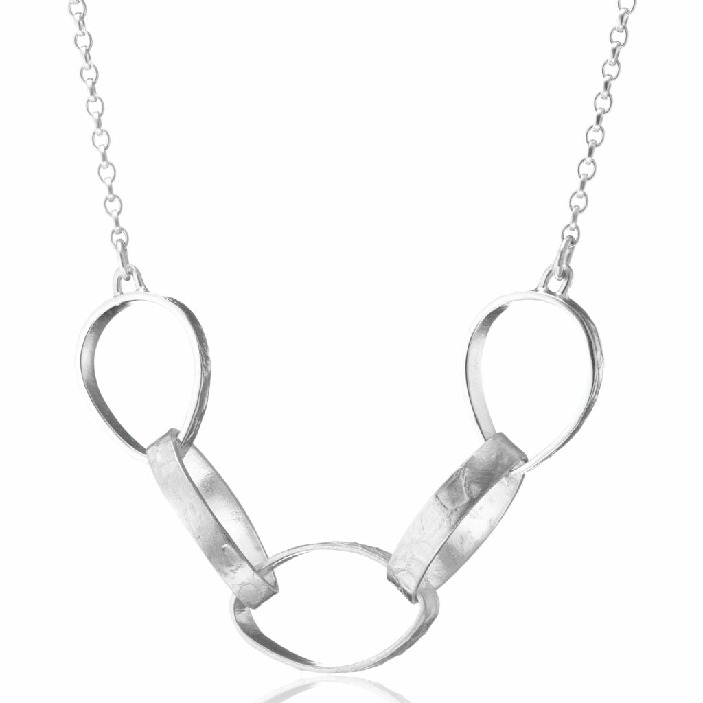 A Lynsey de Burca Talún Chain Neckpiece with a unique design featuring five interconnected oval loops in the front, three of which are elongated and arranged alternately with two smaller ovals. The simple yet textured chain-link enhances the elegant look of this jewelry piece.