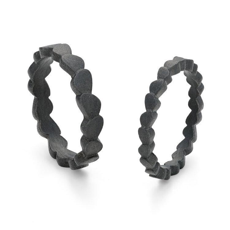 Two black textured hoop earrings from the Kimana collection, featuring a unique, wavy, and scalloped design. The earrings have a contemporary and artistic appearance, combining both modern and organic elements. They are placed upright on a white background.
The Kimana Oxidised Silver Single Wing Ring from Leoma Drew features an elegant design inspired by natural forms. This ring balances modernity with a touch of organic essence for an extraordinary piece of jewelry.
