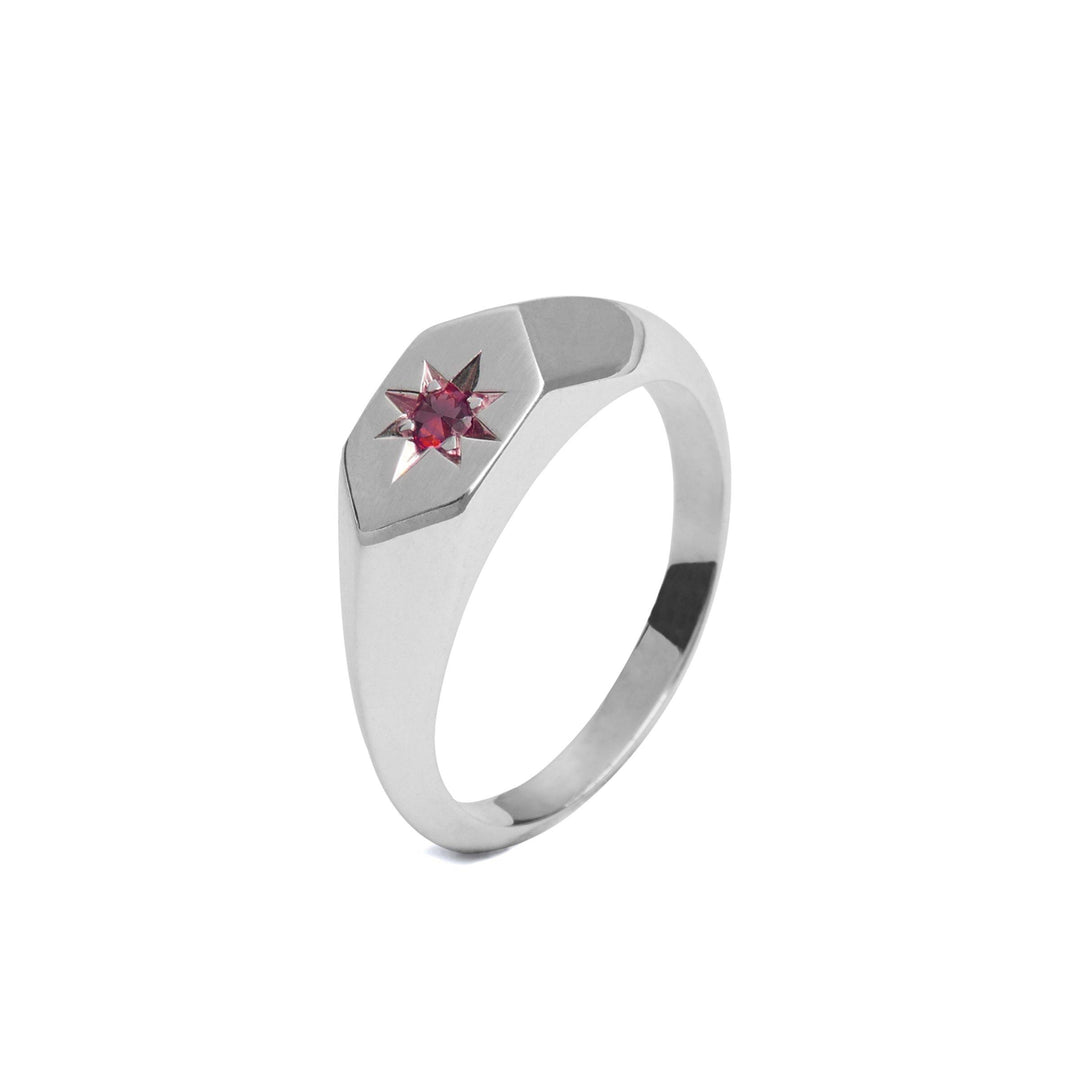 A sleek Starlight Ruby Birthstone Signet Ring from Cosmic Boulevard featuring a hexagonal face with a red star-shaped gemstone set in the center. Handmade in Dublin, this ring showcases a modern and minimalist design with smooth, polished surfaces, perfect for those who celebrate rubies, the birthstone of July.
