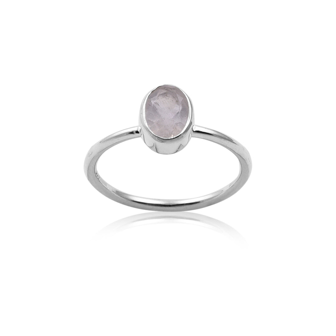 An elegant sterling silver ring featuring a faceted oval rainbow moonstone gemstone set in a simple band. The soft iridescent gemstone is the focal point, with the polished silver band reflecting light subtly. This piece of handmade jewelry from Watermelon Tropical has a minimalist design, emphasizing the beauty of the moonstone.
