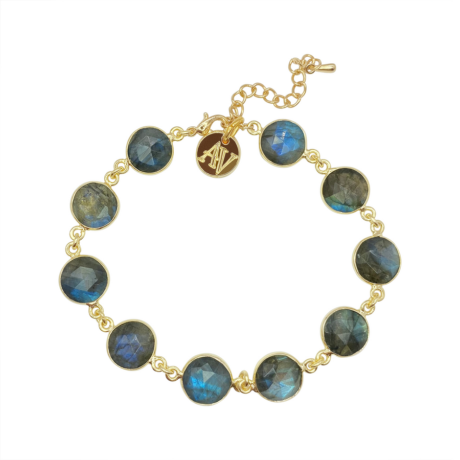 Introducing the handcrafted Aurora Bracelet by Aria V, a gold chain masterpiece featuring multiple round, faceted blue labradorite stones. The bracelet includes a small gold charm with the initials "AV" and an adjustable clasp for the perfect fit.