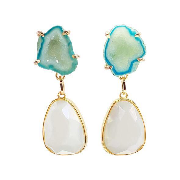 A pair of handpicked Hope Earrings featuring rough, aqua blue quartz stones in 16 carat gold plated settings at the top with smooth, translucent white teardrop-shaped stones hanging below in gold-tone frames by Aria V.