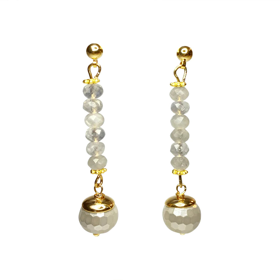 A pair of Aria V Solas Earrings featuring a gold stud at the top, followed by a vertical line of six faceted moonstones. At the bottom, a gold and white speckled, spherical bead hangs from each earring. Expertly handmade in Ireland.