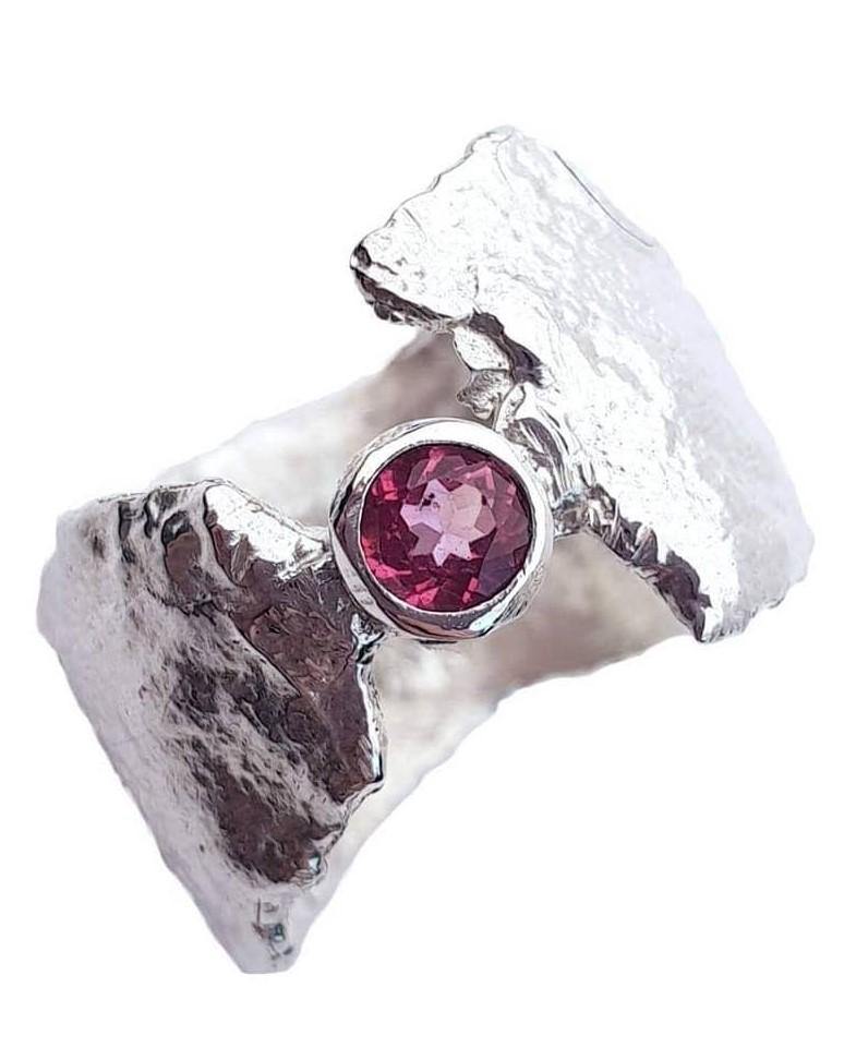 The Caroline Stokesberry-lee Pink Topaz Faerie Tale Ring with a textured, rugged design features a prominent, 4mm Pink Topaz gemstone set in the center. The uneven, raw edges give the ring a unique, handcrafted appearance.