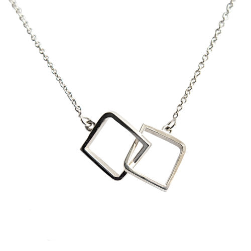 A dainty piece, this **Miriam Wade Le Cheile Square Pendant Silver** necklace showcases two interlocking open square pendants—one with a polished silver finish and the other with a black finish. The 16 inch chain adds to its delicate charm. Perfect for those who appreciate fine, sterling silver pendant jewellery against a plain white background.