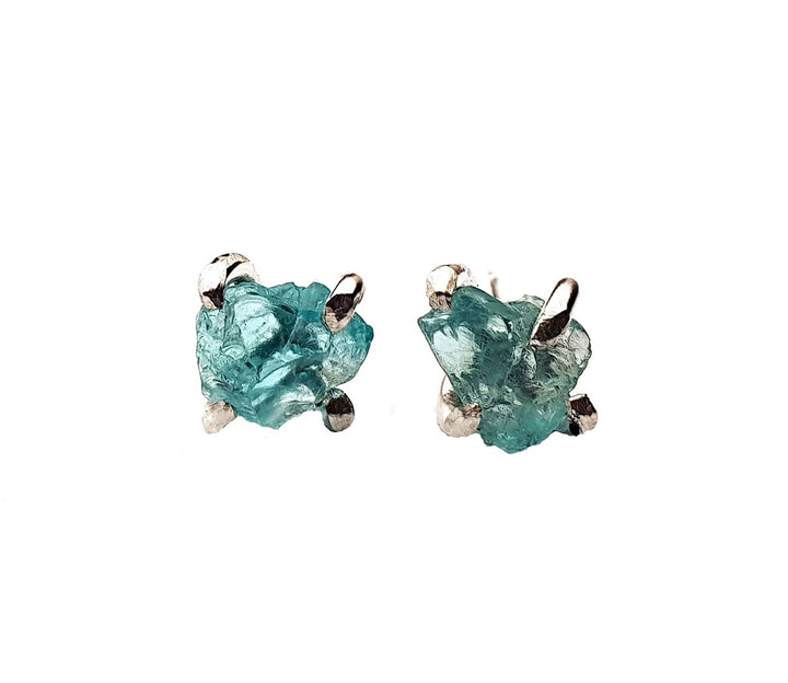 A pair of Caroline Stokesberry-lee Raw Blue Apatite Stud Earrings set in a simple, minimalist sterling silver prong setting. The stones appear unpolished and natural against a plain white background, highlighting their organic shape and vibrant color.