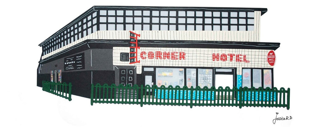 An illustration of a two-story building labeled "Corner Hotel" with a black exterior, large windows on the upper level, and a green fence surrounding it. The artist's signature, Jessica R.D, is in the bottom right corner.