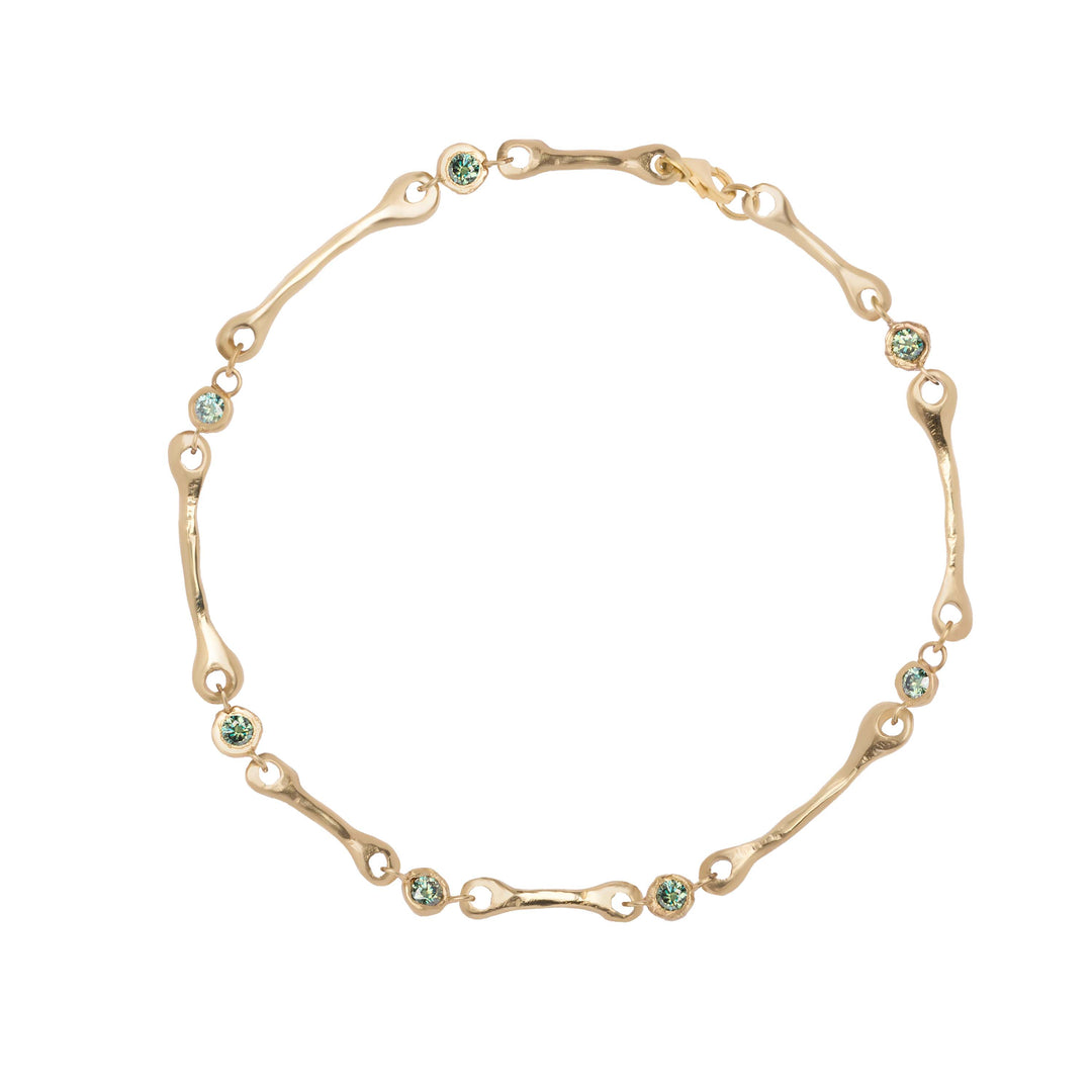 Madeleine Blaine Relic Necklace in gold featuring organic, bone-like links interspersed with small, light green round gemstones for a touch of vintage elegance.