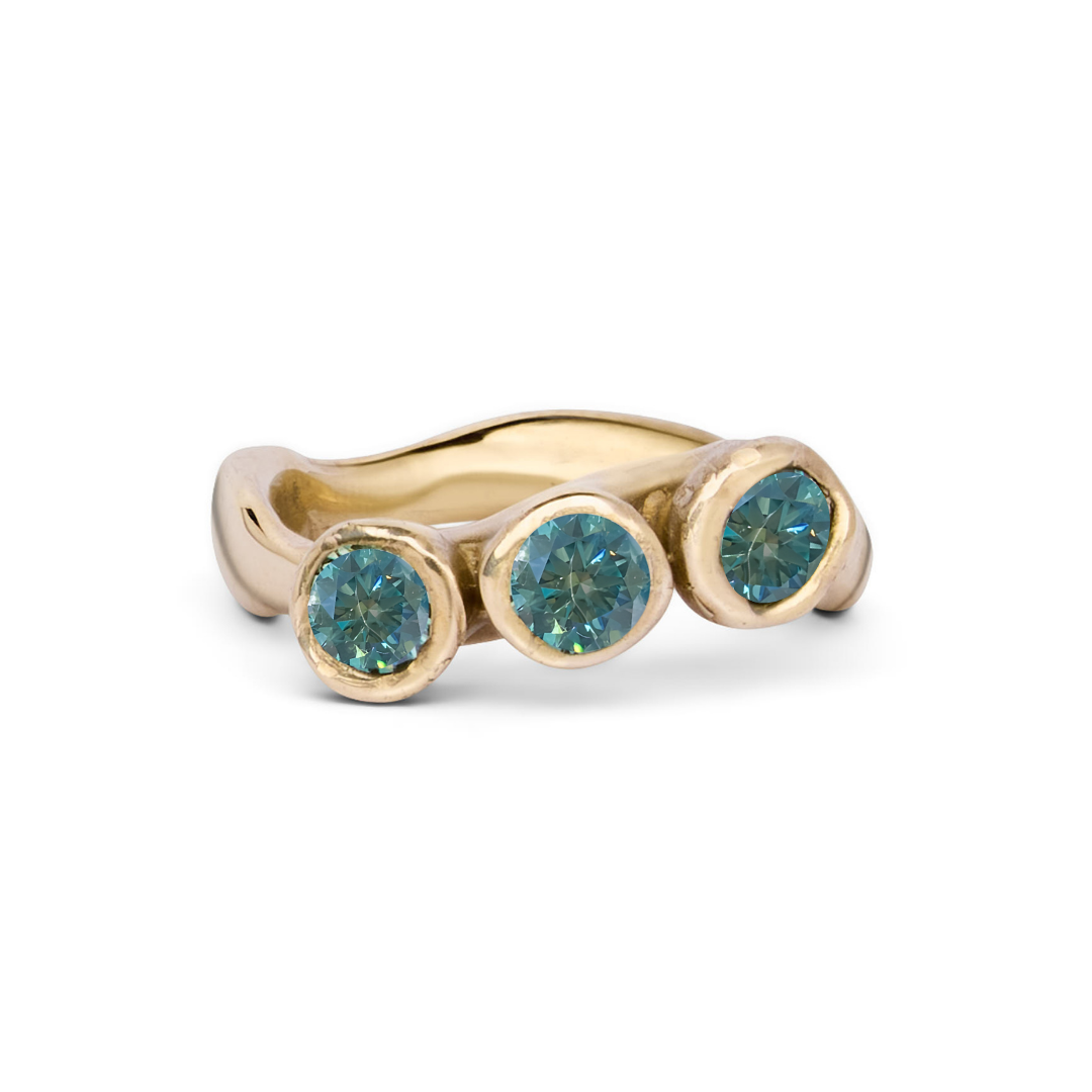 The Moonwater Ring by Madeleine Sculptural Jewellery is a handmade gold ring with a wavy band and three teal gemstones in bezel settings—an elegant, sustainable accessory.