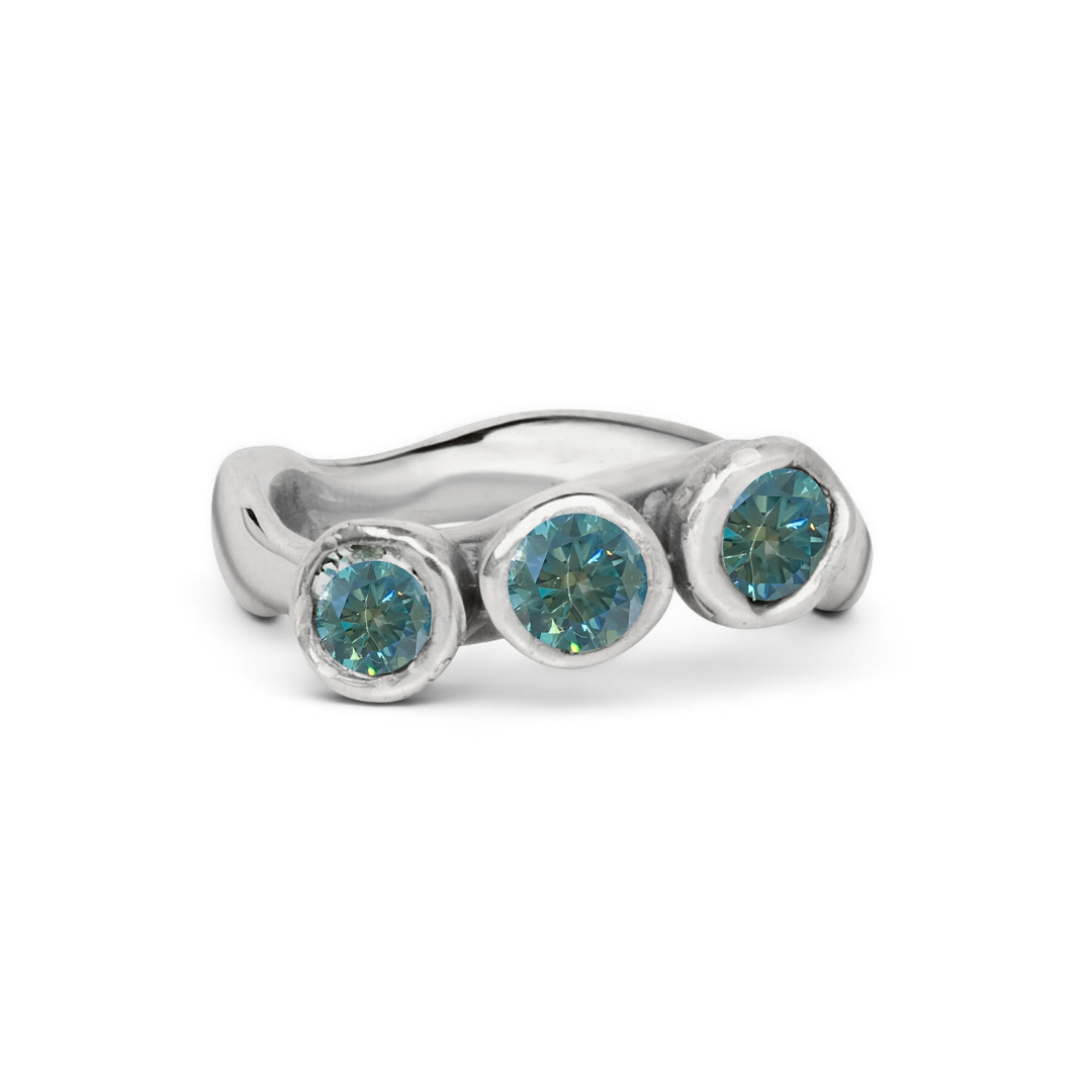 The Moonwater Ring by Madeleine Sculptural Jewellery features a hand-carved silver wavy band with three round teal gemstones in bezel settings—an elegant, unique piece for lovers of distinctive craftsmanship.
