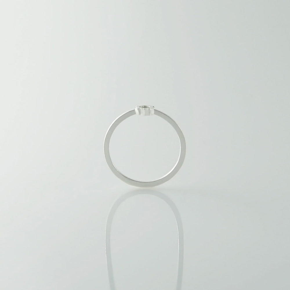 A sterling silver ring with a small, single diamond on top is photographed against a plain, light background. The Fruit Bijoux Minimal Ring Silver tops are viewed from the side, showcasing their minimalist design and the brilliance of the diamond.