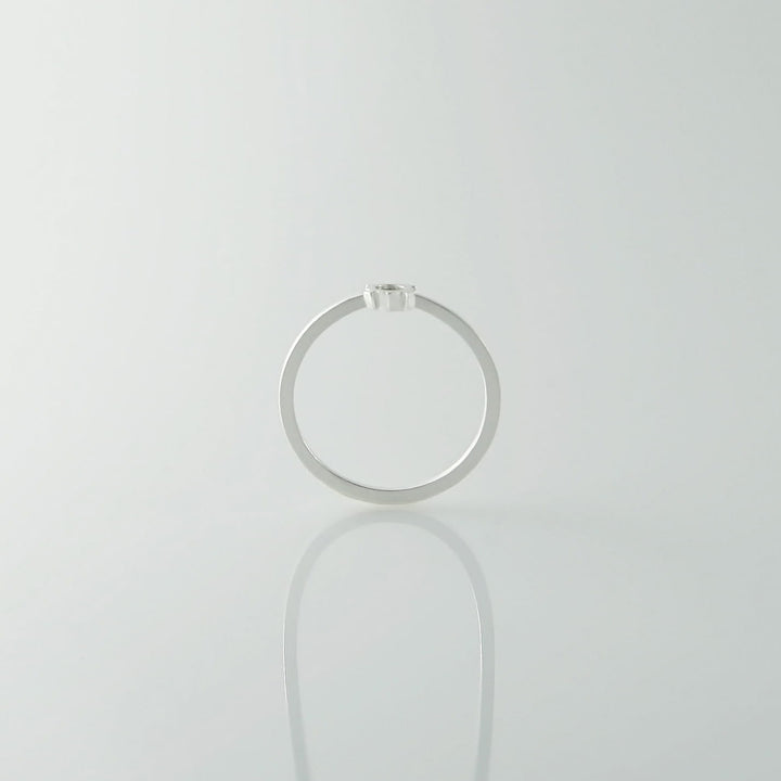 A sterling silver ring with a small, single diamond on top is photographed against a plain, light background. The Fruit Bijoux Minimal Ring Silver tops are viewed from the side, showcasing their minimalist design and the brilliance of the diamond.